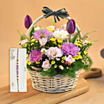 Striking Mixed Flowers Round Basket With Purple Pearl Rakhi